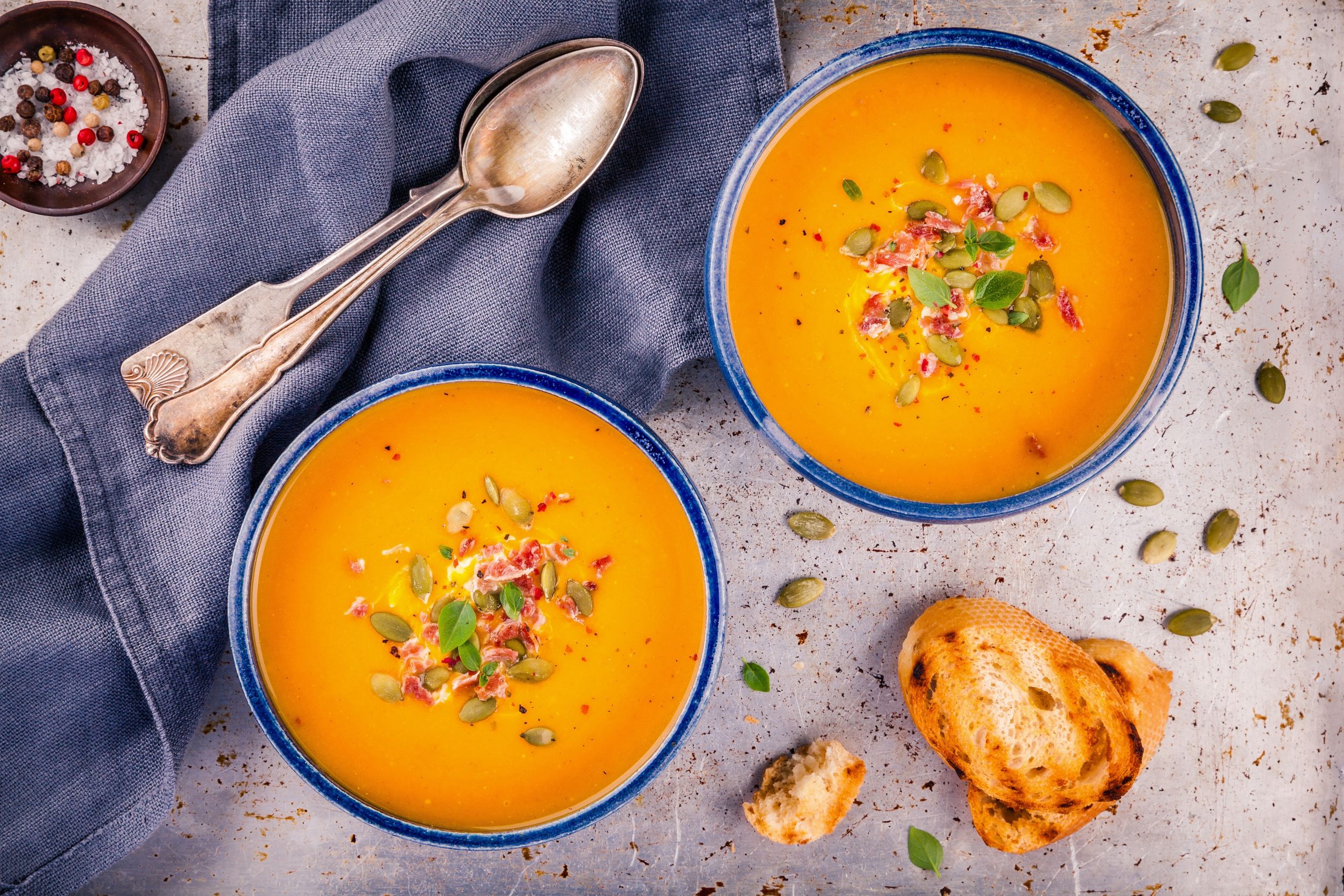 64614934 - homemade autumn butternut squash soup with pumpkin seeds, bacon and basil on rustic background